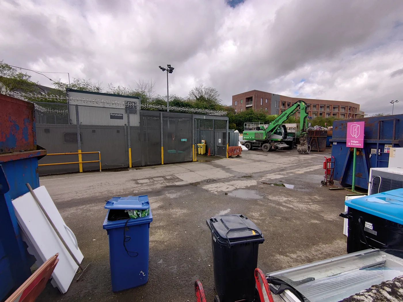Barrowell Green recycling centre in Winchmore Hill, with a blue-lidded and a black-lidded Enfield bin left at the containers. The site is closed on Mondays and every vehicle needs an appointment